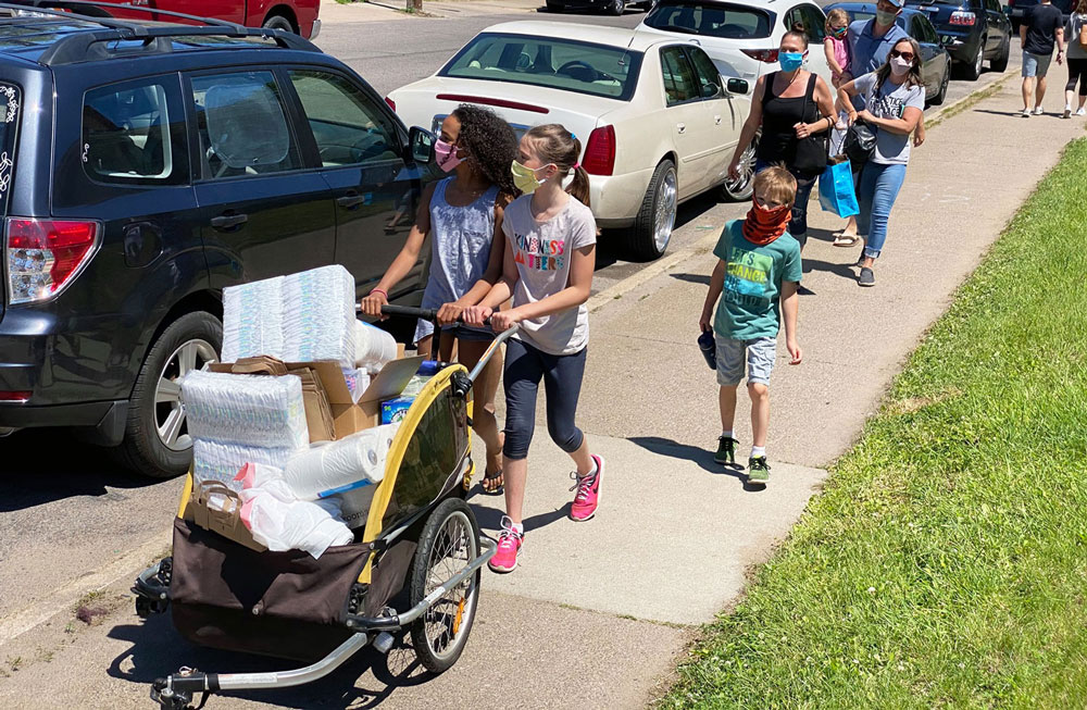Young girls delivering donations to a community of color.